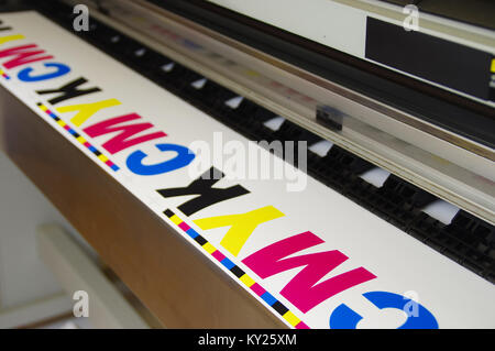 Digital large inkjet machine. Plotter printed CMYK test on white paper. Stock Photo