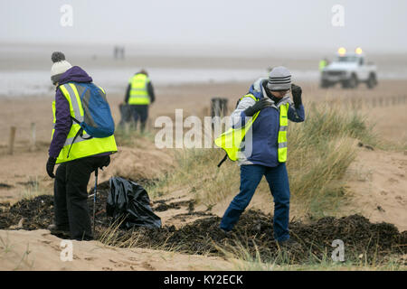 Foreshore cleaning on Aindsdale beach, Southport. 12th December, 2018. UK Weather. Foggy day for volunteers and additional community helpers who clean up after recent storms which have left behind drinks cups, cutlery, straws, plastic bottles, lids stirrers, buckets, polythene, single-use, throwaway items, string, rope, lighters, man-made chemicals, and litter debris in the strandline. Storm Eleanor has left beaches littered with items scooped up from the seabed by the waves described as a tidal wave of waste and removing it is huge task. Stock Photo