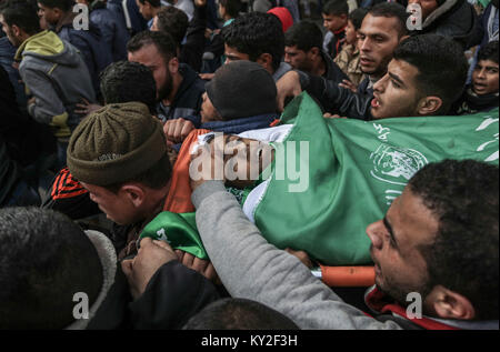 GRAPHIC CONTENT: Maghazi refugee camp, central Gaza Strip, 12 January 2018. Relatives and mourners carry the body of 16-year old Amir Abu Musaed during his funeral at the The teenager was shot during clashes between Palestinians and Israeli forces along the Gaza border on Thursday. Photo: Wissam Nassar/dpa/Alamy Live News Stock Photo