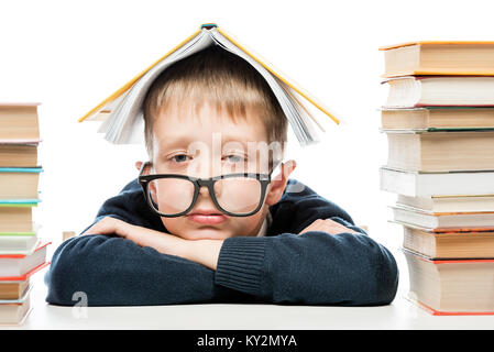 portrait of a tired schoolboy wearing glasses with a book on his head Stock Photo