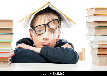 tired schoolboy and piles of books on white background, close-up portrait Stock Photo