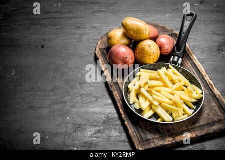 Sliced potatoes in an old frying pan. On the black chalkboard. Stock Photo