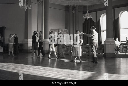 1970s, England, older men and women enjoying the social activity of an afternoon tea dance in a ballroom of a hotel. Stock Photo