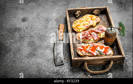 Various sandwiches with seafood, meat and vegetables on an old tray. On a rustic background. Stock Photo