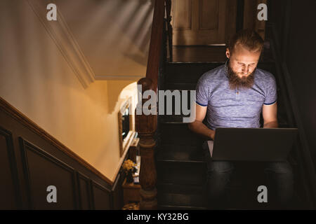 Man using his laptop while sitting on staircase Stock Photo