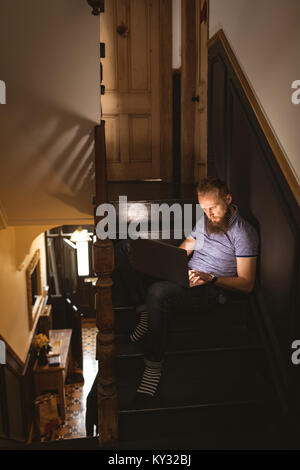 Man using his laptop while sitting on staircase Stock Photo