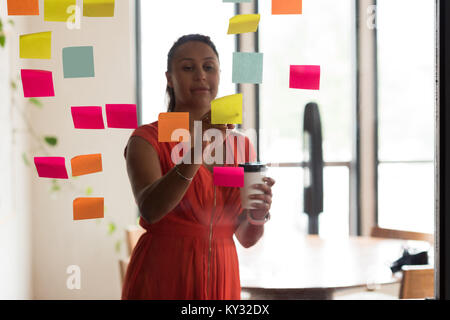 Female executive writing on sticky notes Stock Photo