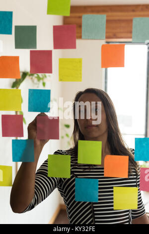 Female executive writing on sticky notes Stock Photo