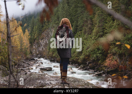 Woman standing near the river in autumn forest Stock Photo