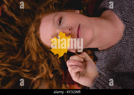 Woman lying down and holding a maple leaf Stock Photo