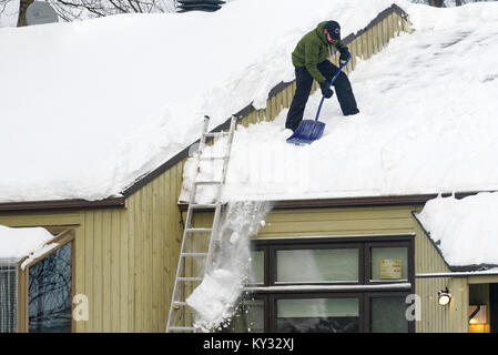 A man clearing snow from the roof of a house, Quebec City in winter Stock Photo