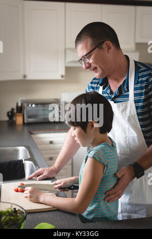 Attentive father helping his son to cut vegetables Stock Photo