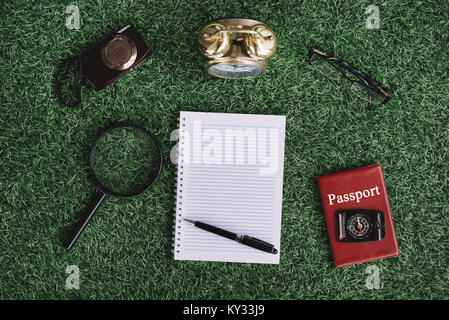 camera, magnifying glass, clock, compass, passport and blank notebook on green grass. travel and holiday concept Stock Photo