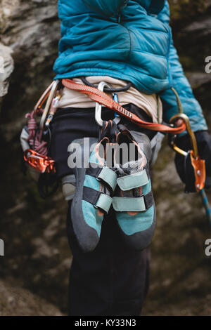 Climber standing with climbing shoes attached to harness Stock Photo