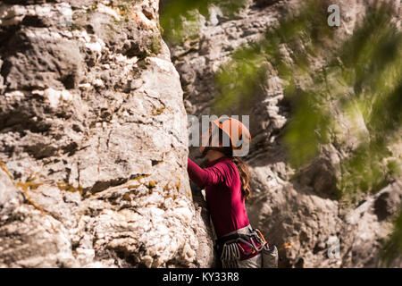 Female rock climber climbing the rocky cliff Stock Photo