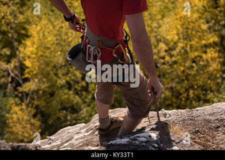 Hiker standing with hiking pole on rocky mountain Stock Photo