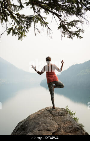 Fit woman balancing on one leg on the edge of a rock Stock Photo