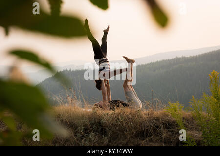 Sporty couple practicing acro yoga in a lush green ground Stock Photo
