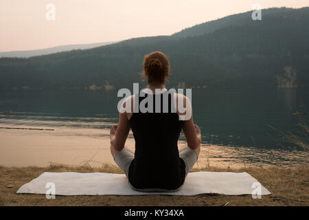 Fit woman sitting in meditating posture on an open ground