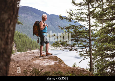 Mature woman standing on rock in the forest Stock Photo