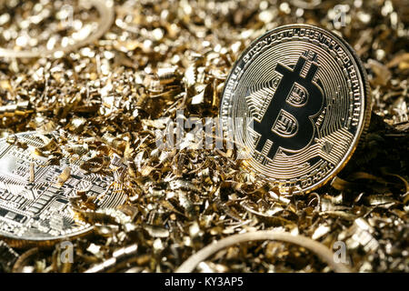 Golden metal coin as symbolic version of Bitcoin on a background of metal shavings . Cryptocurrency and new digital payment system concept. Stock Photo