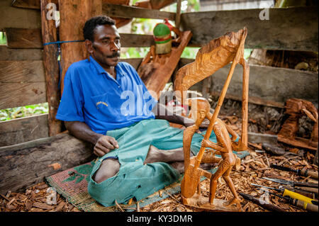 Man from the Asmat Tribe carving with a chisel a statue. Asmat man was making a wood carving. June 27, 2012 Jow Village, Asmat, Indonesia Stock Photo