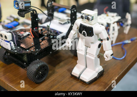 technology, entertainment, machining concept. close up of robotical devices that are placed on the wooden table, one is white and has legs and arms an Stock Photo