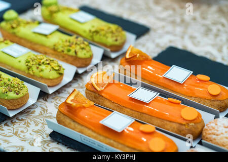 Tasty eclair cakes glazed with orange close Stock Photo