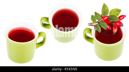 Three green mugs with hot medicinal tea from rose hips. Red rosehip drink and decorative briar twig isolated on white background. Stock Photo