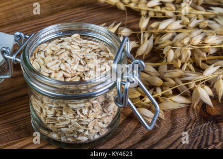 Healthy oat flakes in glass jar. Detail of rolled oats and natural oat on brown wooden background. Stock Photo