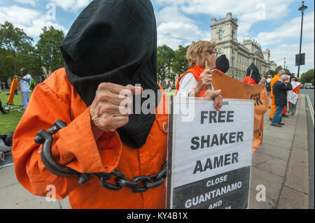 A campaigner in black hood, organd jumpsuit and chains raises a fist in defiance at the weekly vigil for Londoner Shaker Aamer, calling on the UK government to press for his immediate release. Stock Photo