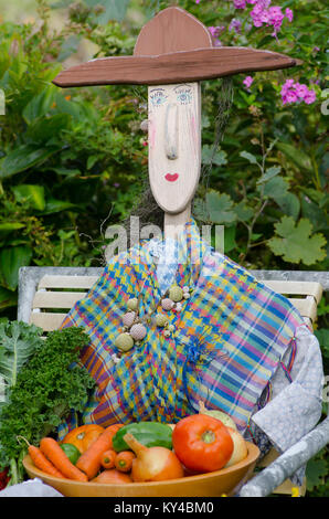 Garden statue and scarecrow dressed up with harvest from community garden, Maine, USA Stock Photo