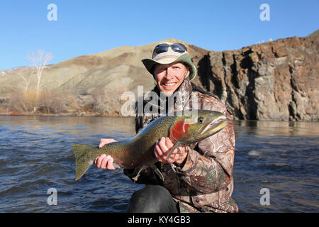 adult fisherman holding a large steelhead trout on the Salmon River Stock Photo