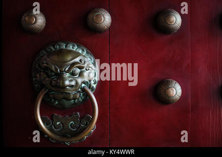 Traditional Chinese doors with brass lion head door knockers and ornamental studs. The number of studs represent status of the owner. Stock Photo