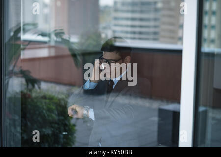 Businessman talking on phone while checking time Stock Photo