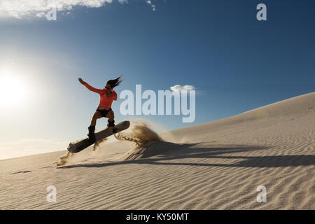 Man sandboarding on sand dune Stock Photo