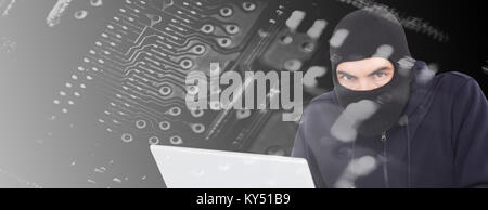 Composite image of hacker in balaclava hacking a laptop Stock Photo