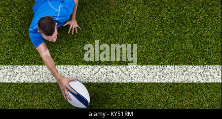 Composite image of rear view of rugby player lying in front with ball Stock Photo