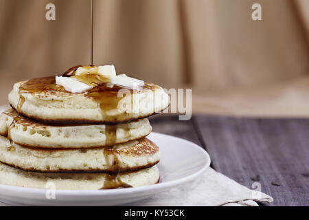 Stack of homemade pancakes with melting butter and syrup being poured onto them. Extreme shallow depth of field. Perfect for Shrove Tuesday. Stock Photo