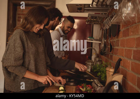 Friends preparing food in kitchen Stock Photo