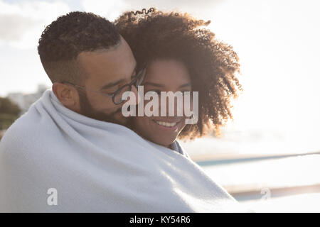 Couple wrapped in shawl near a beach Stock Photo