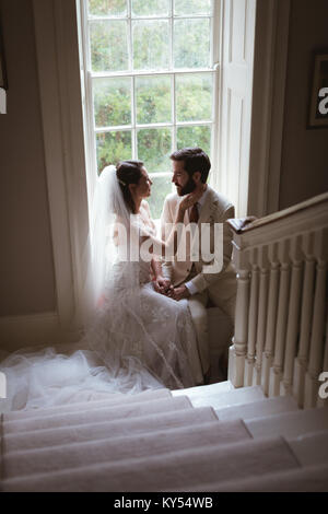 Romantic bride and groom sitting on the window sill Stock Photo