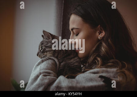 Close-up of beautiful woman smelling her pet cat Stock Photo