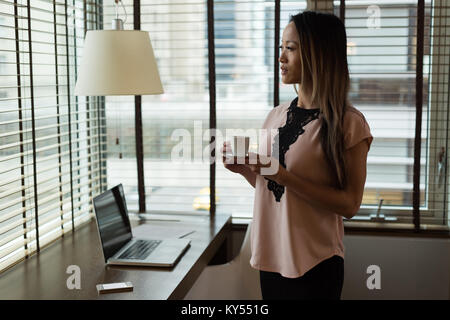 Businesswoman looking away while having coffee Stock Photo