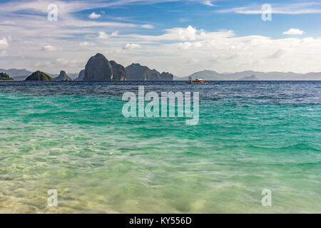 Small islands sat on the horizon taken at a low angle over an empty calm tropical sea  with depth of field. Stock Photo