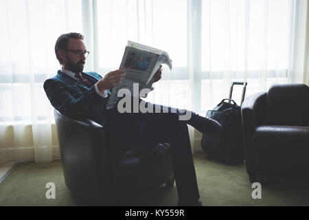 Businessman reading newspaper on arm chair Stock Photo