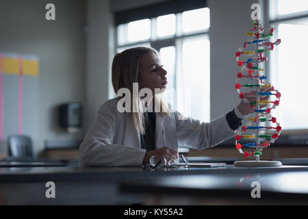 Teenage girl examining the molecule model in laboratory