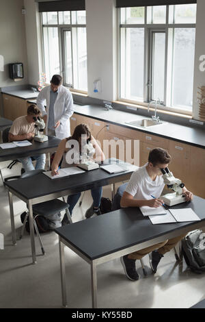 Teacher assisting students in experiment Stock Photo