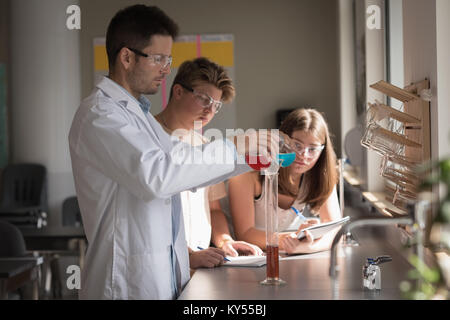 Teacher assisting students in chemical experiment Stock Photo