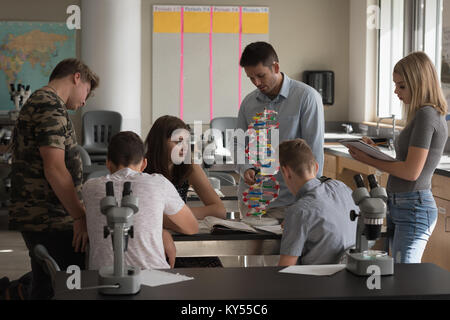 Teacher assisting students in experiment on molecule Stock Photo